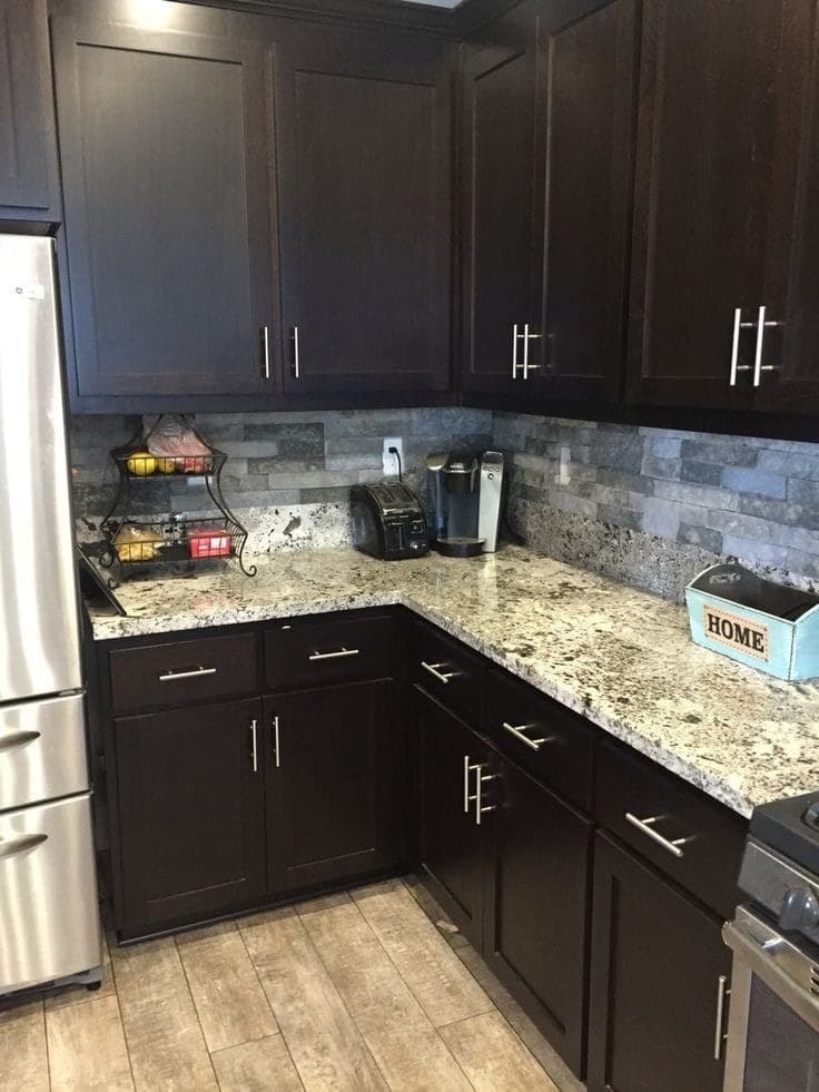Speckled granite over espresso cabinets with stacked stone backsplash