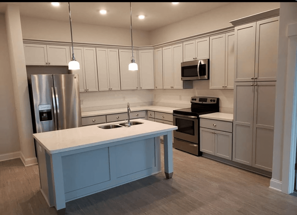 White quartz island with grey cabinetry and pendant lighting