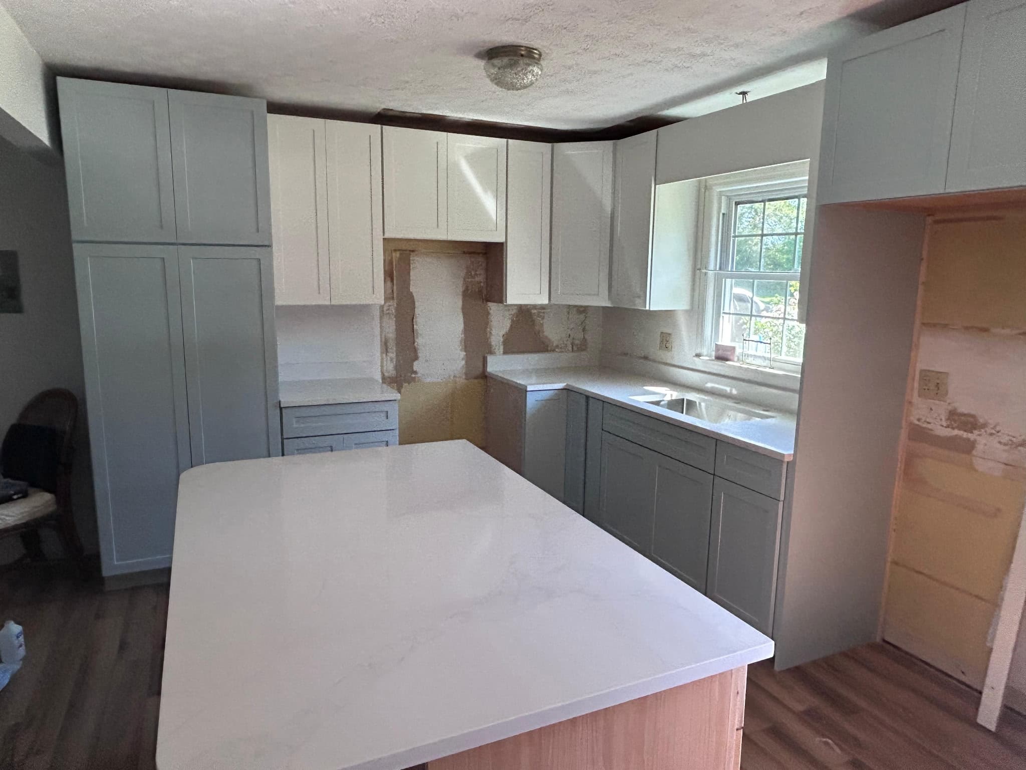 White quartz waterfall island with grey shaker cabinets