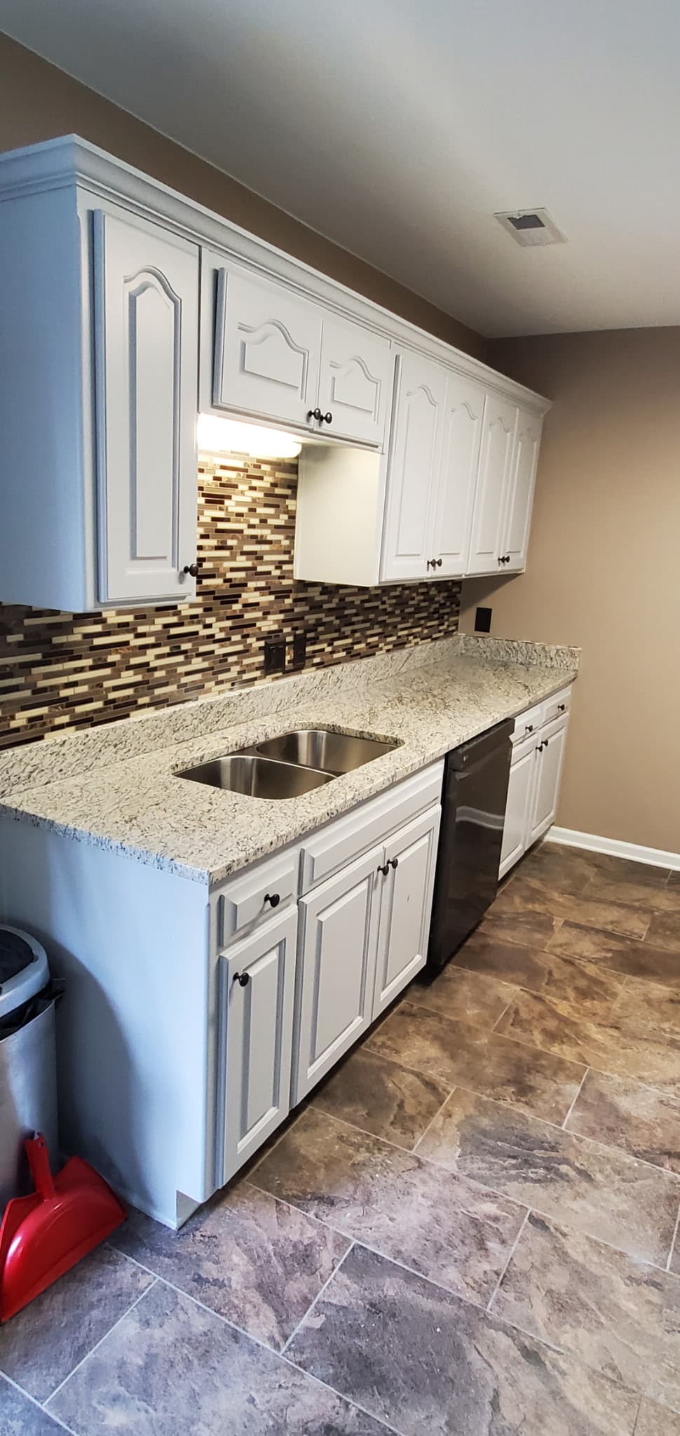 White granite counters with double sink and mosaic backsplash